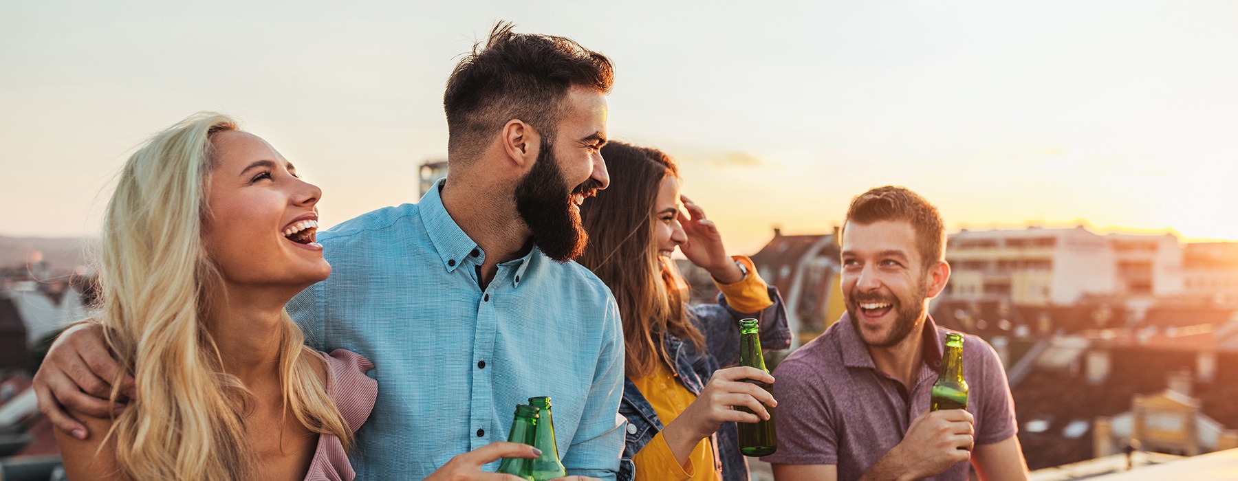 friends laughing on a rooftop drinking beer